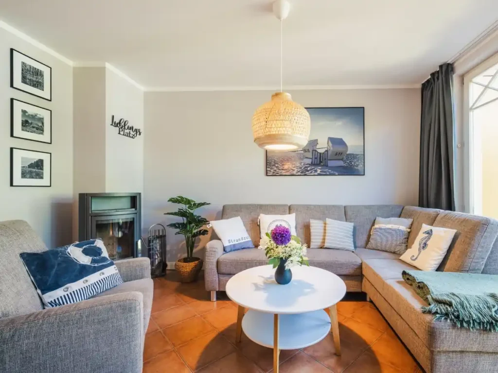 Eine gemütliche Sitzecke in der Zingster Ferienwohnung privat. An der Wand steht ein Kamin und an der Wand hängen dekorative Bilder.